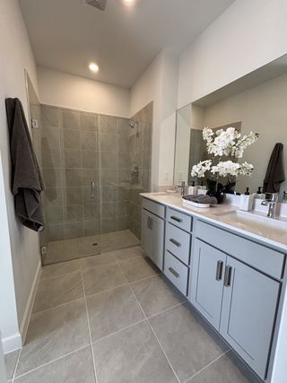 Elegant bathroom with a sleek glass shower, dual sinks, and soft gray cabinetry creating a serene oasis.