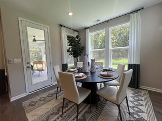 Model Home A cozy dining area with a round table, elegant chairs, and large windows offering scenic views.