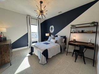 A modern bedroom with a geometric accent wall, stylish lighting, and a sleek workspace.