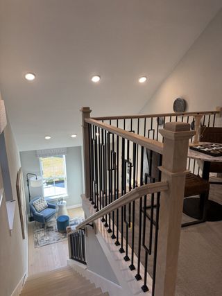 Model Home A modern staircase with sleek railings, abundant natural light, and cozy seating area below.