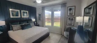 A cozy bedroom featuring plush bedding, dark accent wall, and elegant decor with large windows for natural light.