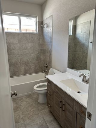 A sleek bathroom featuring gray tile, a modern vanity, and a large mirror for a contemporary look.
