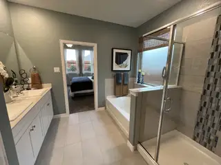 A modern bathroom featuring dual sinks, a glass shower, and a tub with tasteful decor.