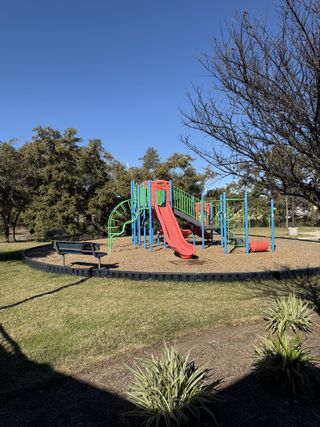 Community Amenities A vibrant playground with a red slide and climbing structures in Carneros Ranch by Coventry Homes (Leander, TX).