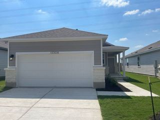 A modern gray home with a spacious garage and neat lawn in the Durango community by D.R. Horton (Mustang Ridge, TX).