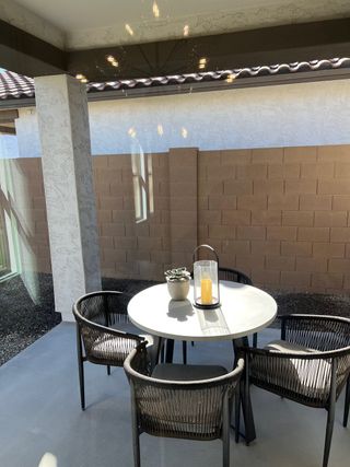 A cozy patio with modern wicker chairs and a round table, perfect for outdoor dining and relaxation.