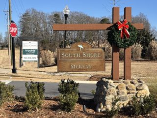 Street view Welcome to McLean South Shore by Tri Pointe Homes, Belmont, NC; a picturesque community entrance adorned with festive wreaths.