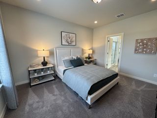 A cozy bedroom with a soft neutral color palette, an upholstered bed, and matching bedside tables with elegant lamps. The entrance to the en-suite bathroom enhances the convenience and comfort of the space.