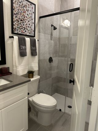 A chic bathroom with sleek gray tiles, a glass-enclosed shower, and elegant modern decor.