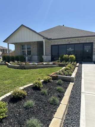 A charming brick home with manicured gardens at Sundance Cove by Davidson Homes LLC (Crosby, TX).
