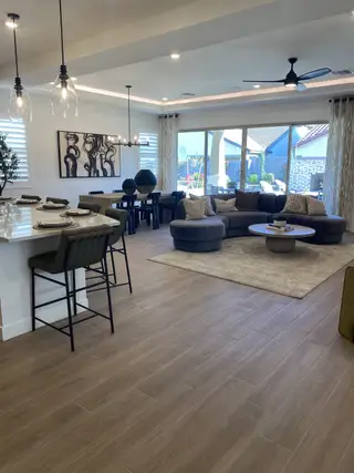 A modern open-concept living area featuring wooden floors, sleek furnishings, and large windows for ample natural light.