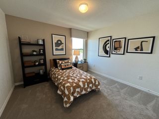 A cozy bedroom with abstract artwork, a geometric-patterned bedspread, and a sleek black shelf.