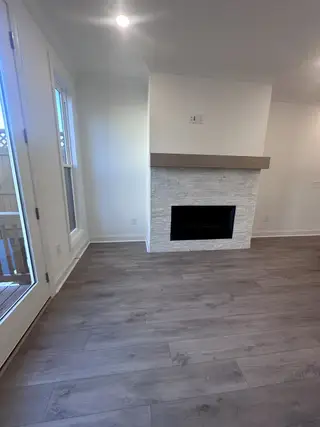 A sleek living area with a modern fireplace, elegant wood flooring, and abundant natural light.