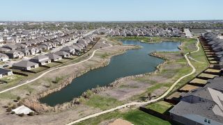Community Amenities Scenic aerial view of Lagos community by Pulte Homes, showcasing beautiful homes and natural ponds in Manor, TX.