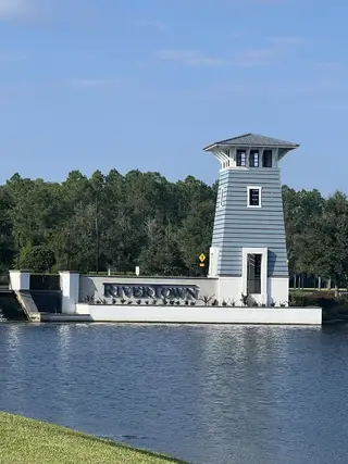 Community Amenities A picturesque tower by a tranquil pond in RiverTown - Bluffs by Mattamy Homes, St. Johns, FL, surrounded by lush greenery.