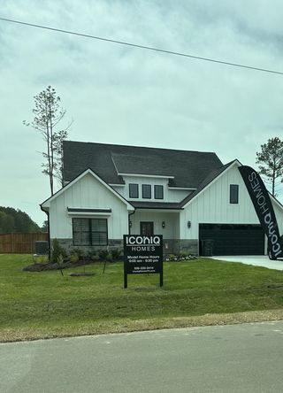 A modern white wood home with dark accents and manicured lawn in Spring Branch Crossing by ICONIQ Homes (Granbury, TX).