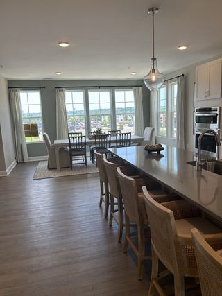 A bright dining area with large windows, elegant pendant lighting, and a spacious island with wooden seating.