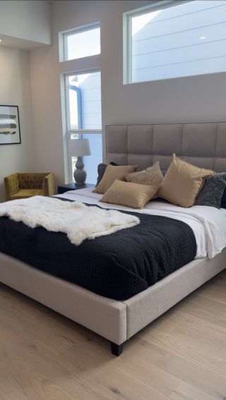 A cozy bedroom featuring a plush bed with neutral tones, soft lighting, and elegant decor.
