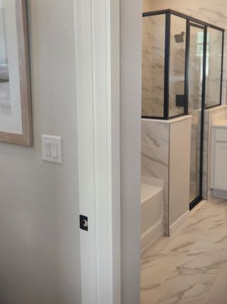 A modern bathroom with a sleek glass shower, marble-patterned tiles, and contemporary design elements.