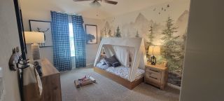 Model Home A cozy children's room with a tent bed, woodland-themed mural, and rustic decor.