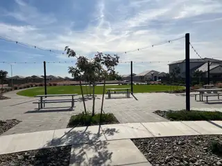 A picturesque community park with seating, pathways, and string lights in Radiance At Superstition Vistas by D.R. Horton (Apache Junction, AZ).