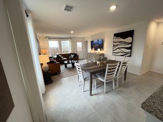 An open-concept dining and living area with natural light, neutral decor, and stylish furnishings.