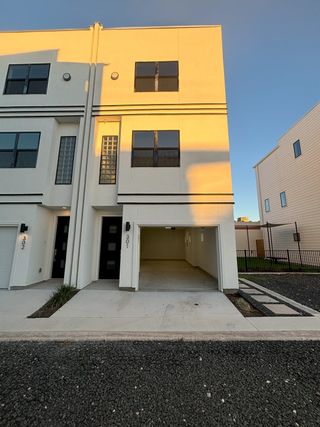 Street view A modern townhome with a private garage and sleek design, showcasing The Deco by Terramark Urban Homes in San Antonio, TX, with unit numbers visible.