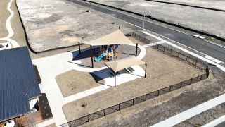 Aerial view of a vibrant playground in University Heights by Scott Felder Homes in Round Rock, TX, with shaded picnic areas and walking trails.