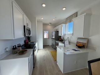 A sleek kitchen with white cabinets, stainless steel appliances, and light wood flooring, offering a bright and modern feel.