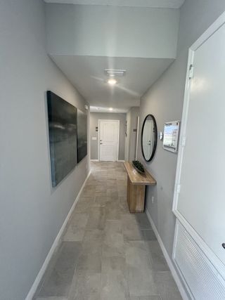 A modern hallway with sleek gray tile flooring, a contemporary console table, and minimalistic decor.