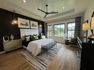 A chic bedroom with a textured black accent wall, elegant lighting, and large windows showcasing scenic views.