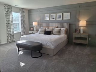 A spacious bedroom with paneled walls, elegant lamps, patterned drapes, and a cozy seating bench by the window.