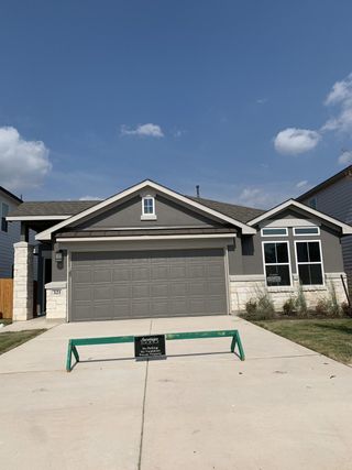 A modern gray home with stone accents and manicured lawn in Morningstar by Saratoga Homes (Georgetown, TX).