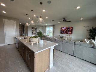 A modern open-concept living area with a large island, cozy seating, and stylish pendant lights.