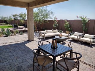 A spacious patio with stylish seating, paver stones, and lush landscaping, perfect for outdoor relaxation and entertaining.