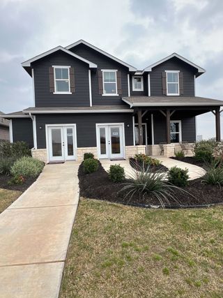 A charming dark-paneled home with a porch and landscaped garden in Paramount by CastleRock Communities (Kyle, TX).