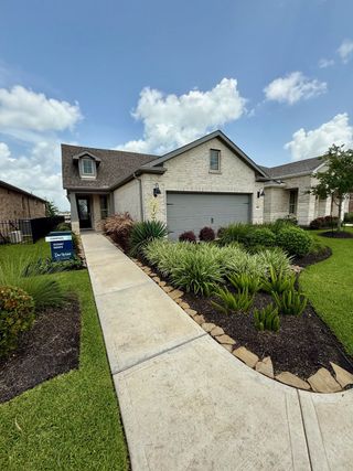 A charming brick home with a landscaped yard in Del Webb Fulshear by Del Webb (Fulshear, TX).