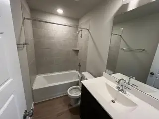 A sleek bathroom with a tiled shower, white vanity, and large mirror, offering a modern and functional design.