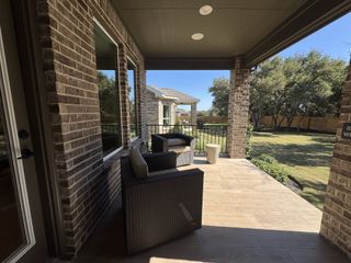 Another angle of the covered patio, showing a fenced backyard with lush grass and mature trees. The extended patio space offers a perfect spot for relaxation.
