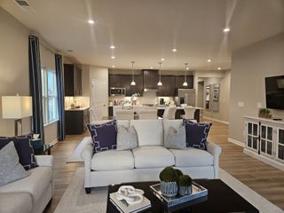 A cozy open-concept living room with modern kitchen, plush seating, sleek cabinetry, and soft lighting.