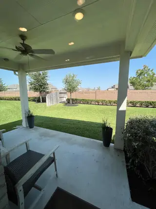A cozy covered patio with seating, ceiling fan, and a lush backyard view. Perfect for relaxation and outdoor enjoyment.