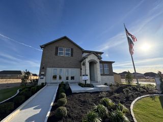 Street view A beautiful two-story brick home with a manicured lawn in The Colony 50s by Ashton Woods (Bastrop, TX).