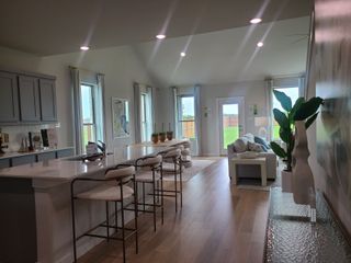 An open living space with sleek kitchen, elegant bar seating, and cozy lounge area, filled with natural light.