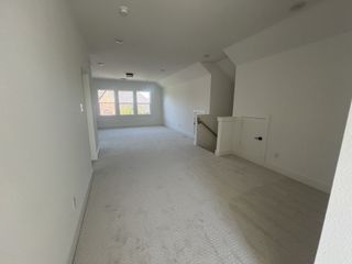 A spacious, carpeted hallway with ample natural light from large windows and modern recessed lighting.