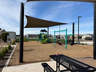 A vibrant playground with shade sails in Bella Vista Trails Classic Series by Meritage Homes, San Tan Valley, AZ.
