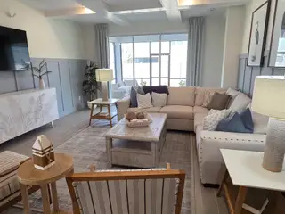 A spacious living room with coffered ceilings, a large sectional, and stylish decor invites comfort and relaxation.