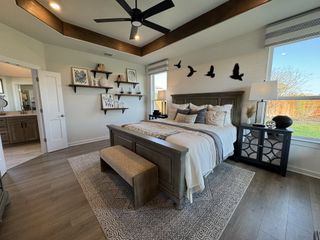 A cozy bedroom with tray ceiling, wood accents, elegant decor, and a large window offering ample natural light.