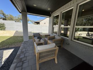 Model Home A cozy patio featuring wooden seating, a tiled floor, and a view of the landscaped backyard.