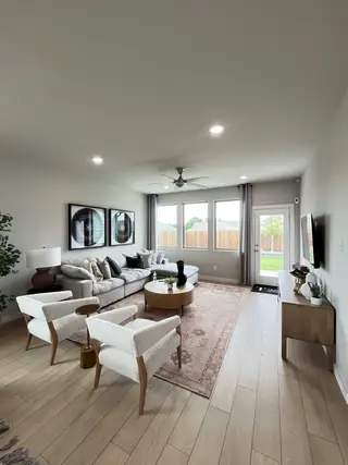 A cozy living room featuring a plush sectional sofa, stylish armchairs, a large window, and elegant decor elements.