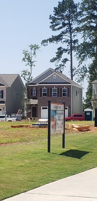 Street view A charming two-story brick home, lush landscaping in Sanders Park by Smith Douglas Homes (Austell, GA).